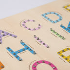 Wooden alphabet board with colorful letters and a pen on a gray background