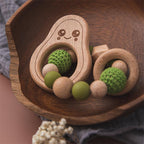 Wooden teething ring with green and beige beads on a wooden tray