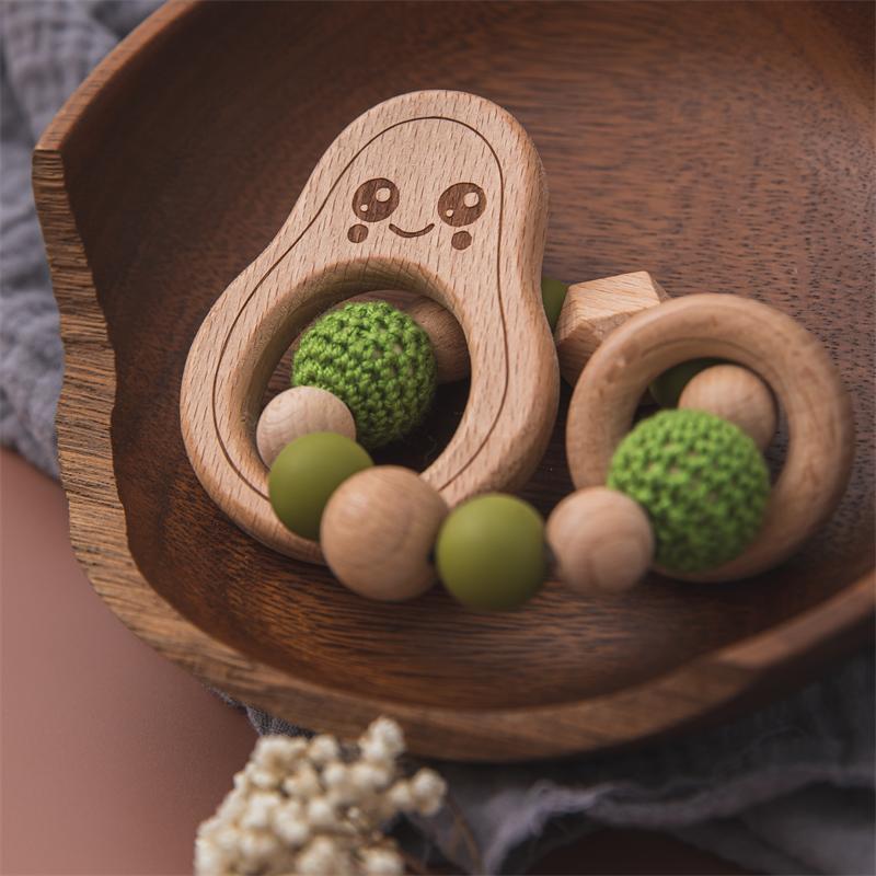 Wooden teething ring with green and beige beads on a wooden tray
