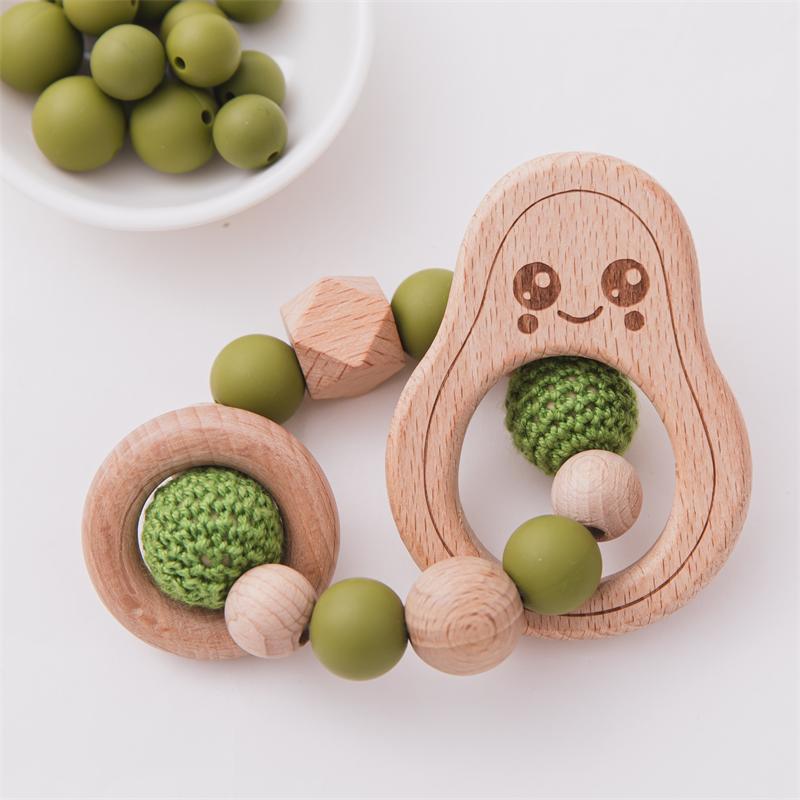 Wooden teething rings with green silicone beads on a white surface