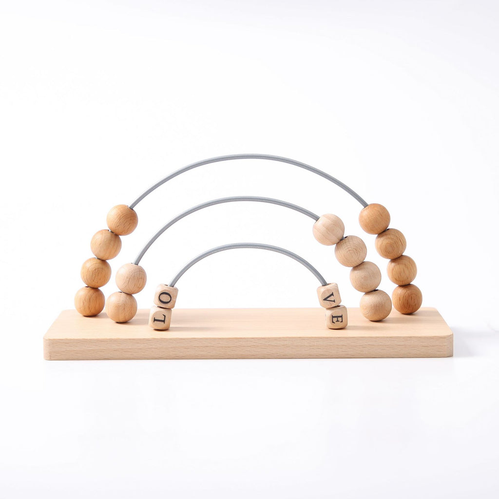 Wooden toy with beads and letters spelling 'LOVE' on a white background