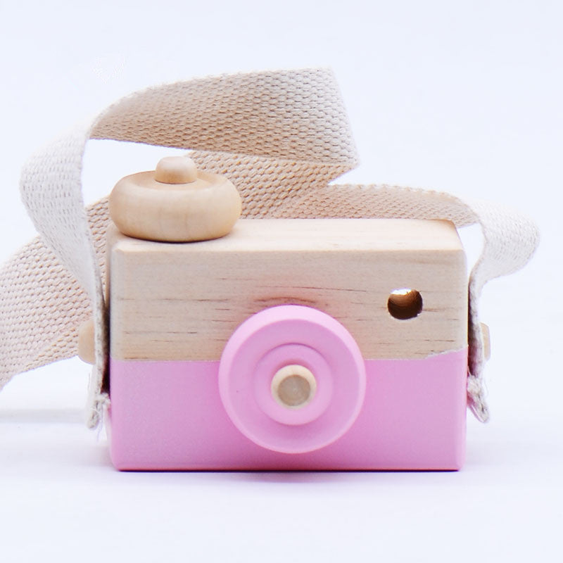 Wooden toy camera with pink accents and a wooden donut on a white background