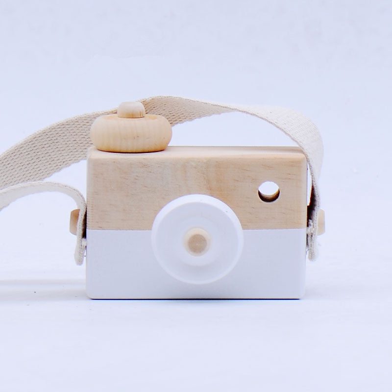 Wooden toy camera with a white base and beige top on a light gray background