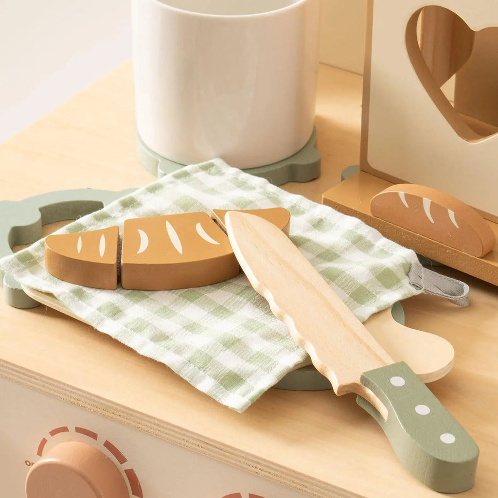 Wooden toy kitchen set with bread and knife on a wooden surface
