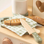 Wooden toy kitchen set with bread and knife on a wooden surface