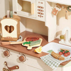 Wooden toy kitchen set with various utensils and appliances on a white background.