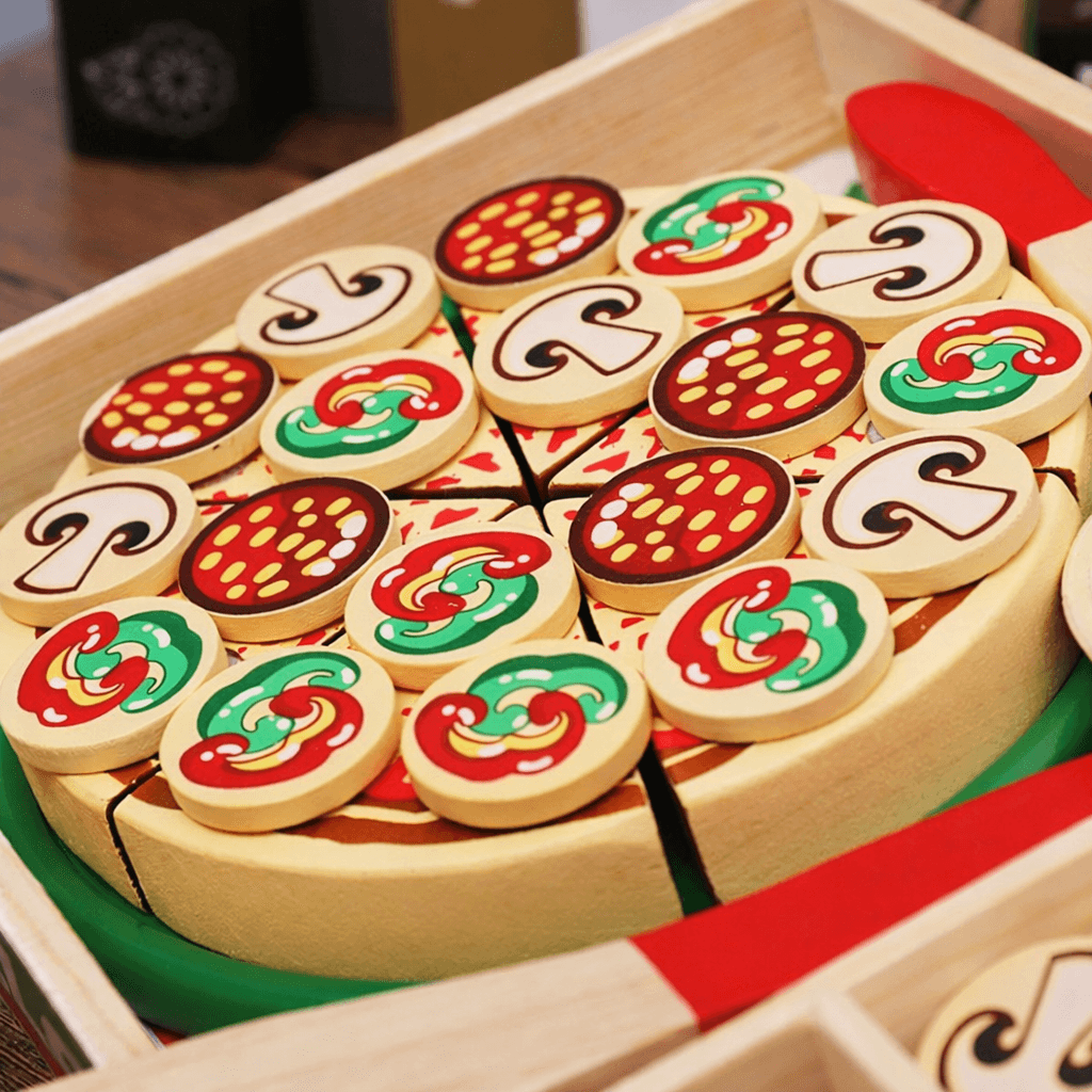 Wooden toy pizza set with various toppings on a wooden tray.
