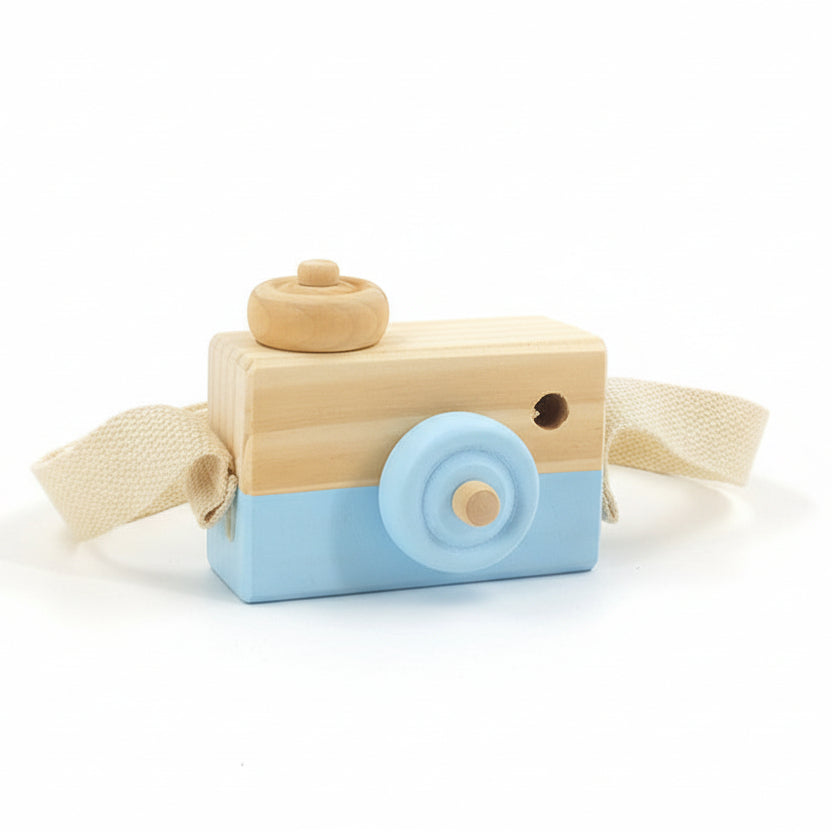 Wooden toy camera with a blue base on a surface with flowers in the background