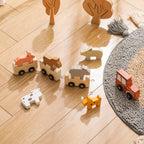 Wooden toy animals on a wooden floor with a rug in the corner.Wooden Splicing Car Toy Set_Wonder Kiiids