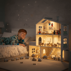 Child in pajamas lying on a bed next to a detailed dollhouse with lights on.Wooden Play House with Lights – Wonder Kiiids
